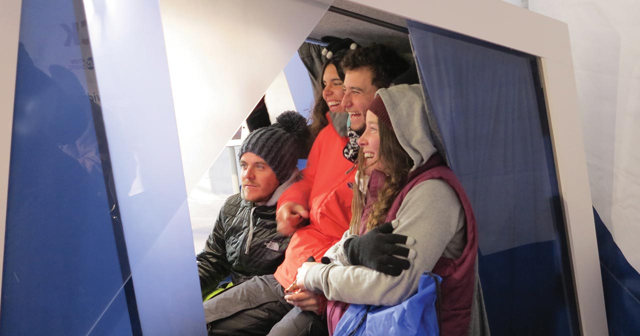 Four people together inside video booth recording a message