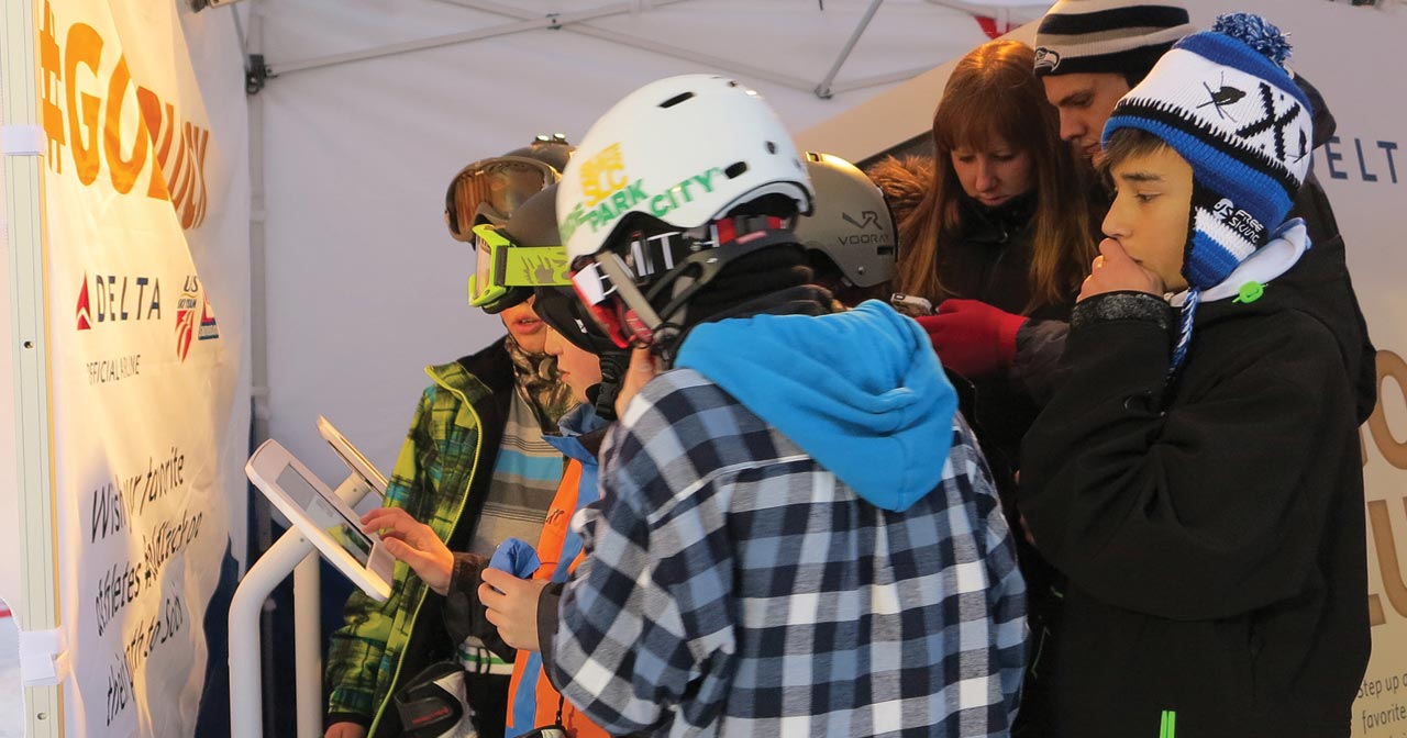 Group of young skiiers/snowboarders share their videos from iPad stands.