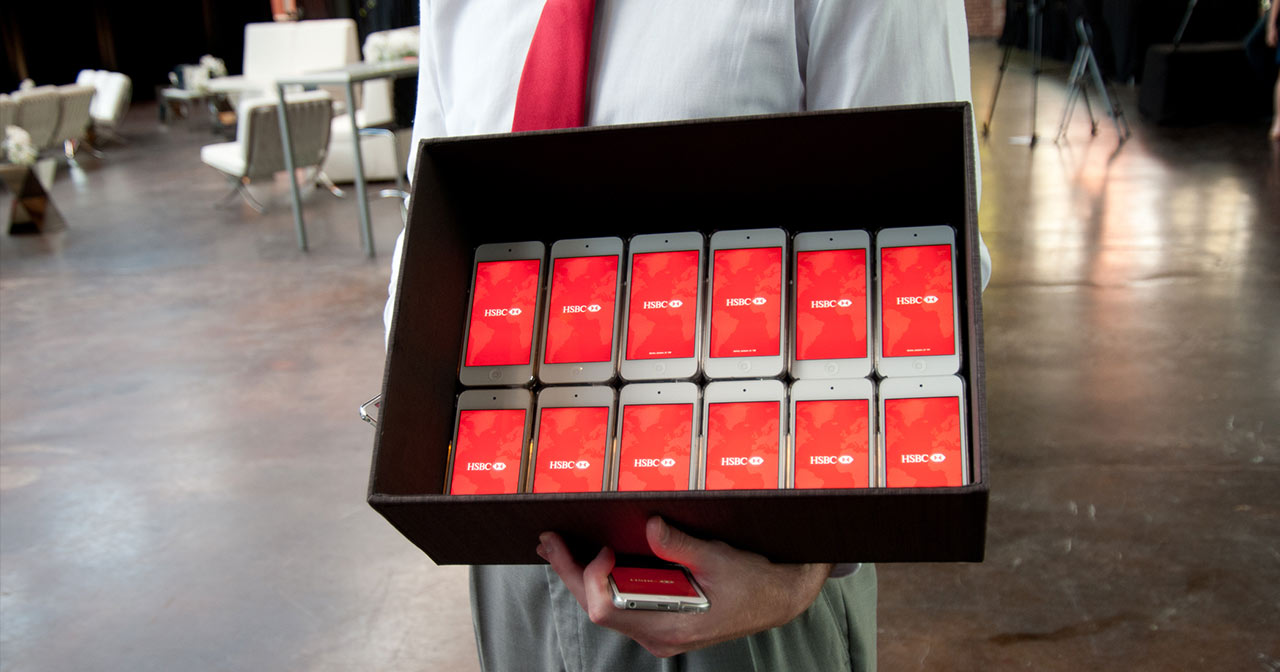 A person holds a box filled with iPods all displaying HSBC logo on the screens