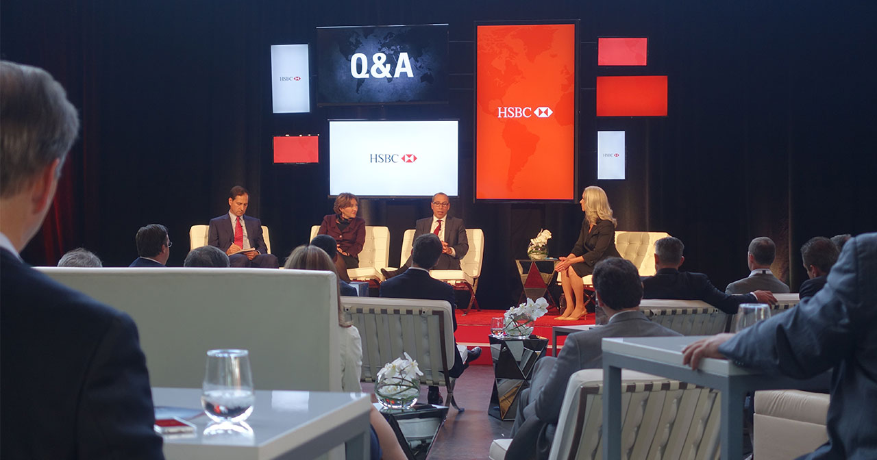 View of stage from the crowd. Panel of 4 people sit on stage with several screens behind them during Q&A segment.