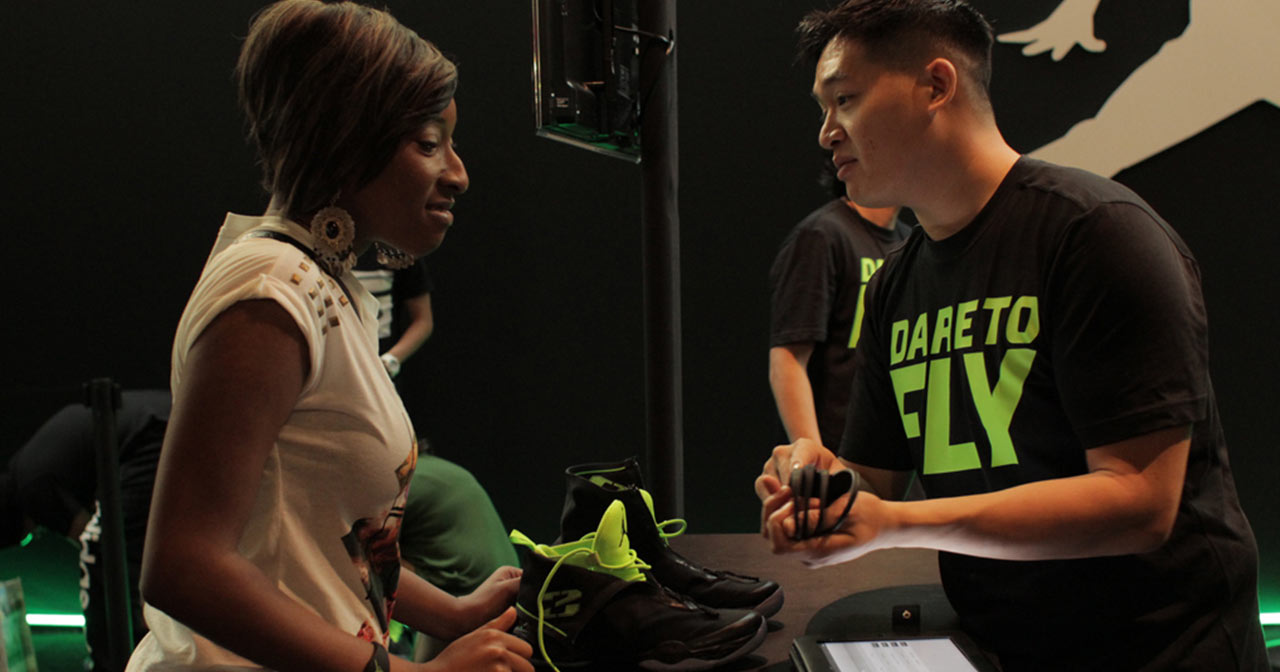 A woman receives her AJXX8 sneakers from a Nike rep