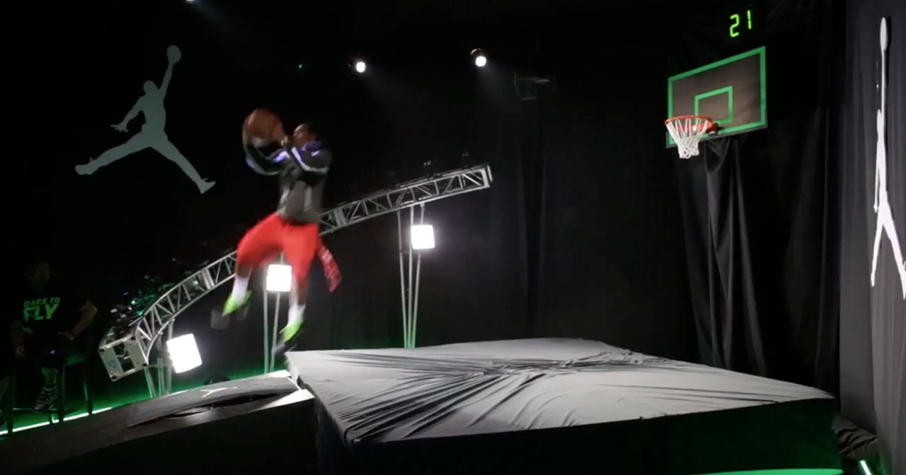 A young man jumping off a springboard in an attempt to dunk a basketball