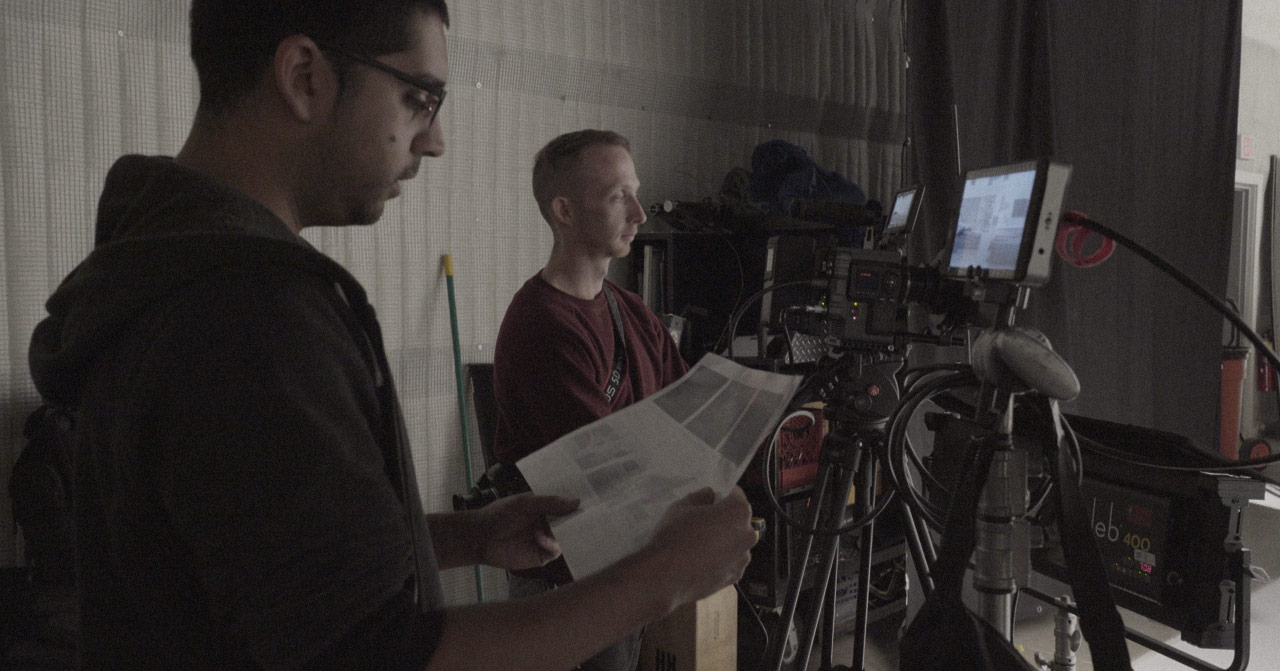 Two people standing behind cameras looking at a storyboard