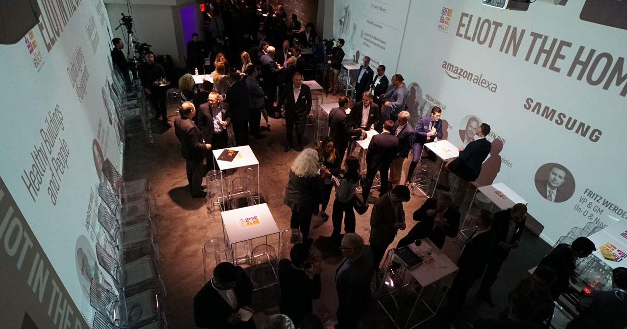 Overhead shot of room full of business people mingling with video projections on the walls.