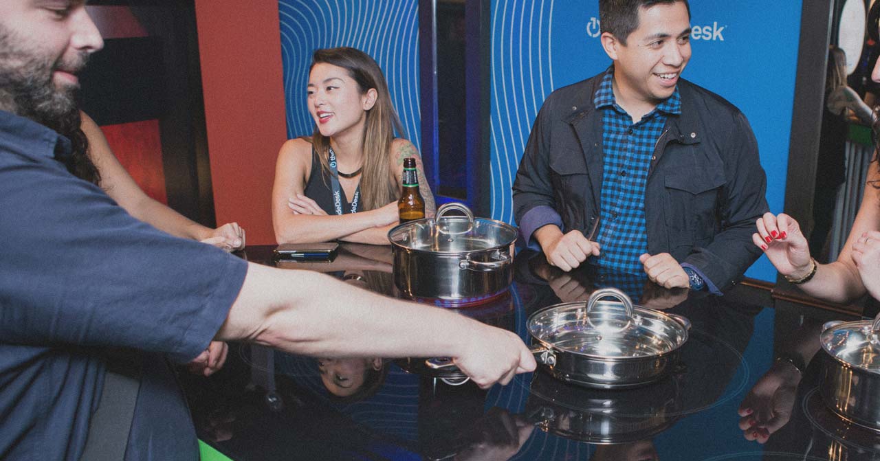 4 people standing around a stovetop